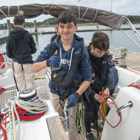 Enfants apprenant la voile à bord d'un voilier en Bretagne, manipulant cordages et équipements nautiques