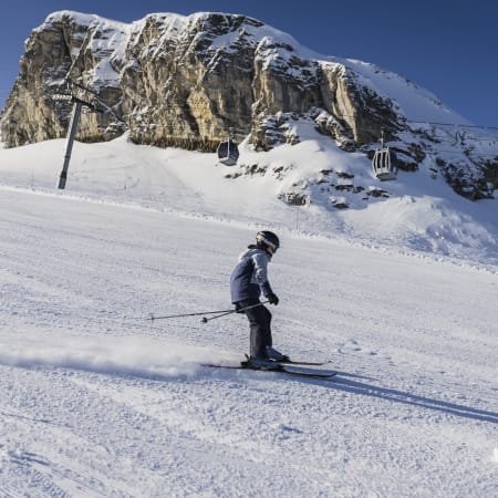 Jeune skieur débutant sur les pistes enneigées de Flaine avec télécabines et falaises rocheuses en arrière-plan