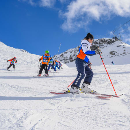 Jeunes skieurs débutants en cours de ski à Val Cenis sur pente enneigée avec moniteur et paysage montagneux