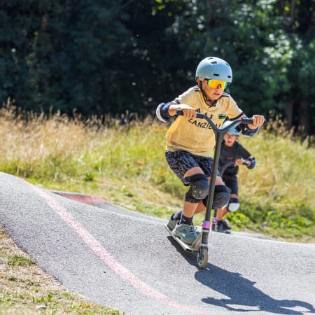 Enfant pratiquant le trottinette en montagne lors d'un séjour multisports à Valloire avec équipement de protection