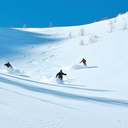 Skieurs en descente sur pentes enneigées de Serre Chevalier, découverte du ski hors-piste en poudreuse avec moniteur