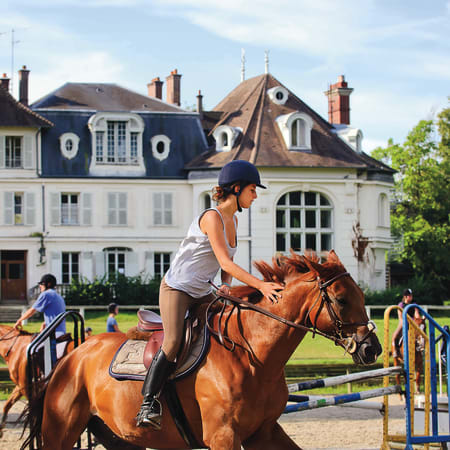 Cavalière à cheval bai devant le manoir du Centre équestre UCPA de Bois le Roi en forêt de Fontainebleau