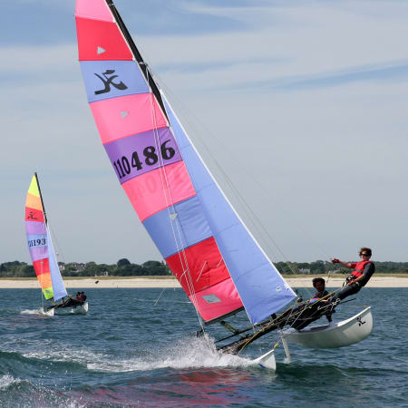 Catamarans de performance avec voiles roses et bleues navigant en mer lors d'un séjour de voile en Bretagne
