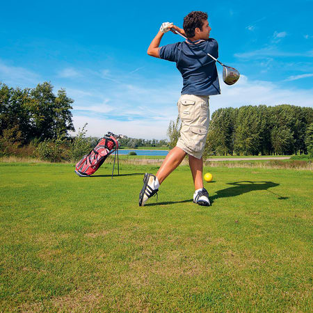 Golfeur en swing sur un parcours de golf verdoyant avec sac de golf rose en arrière-plan