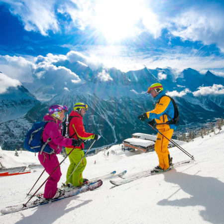 Skieurs en tenue colorée sur les pistes enneigées de Chamonix avec vue panoramique sur la vallée du Mont-Blanc