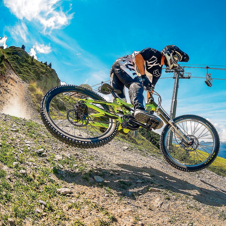 Rider VTT descente en action sur pente alpine avec télésiège et montagnes en arrière-plan aux Arcs