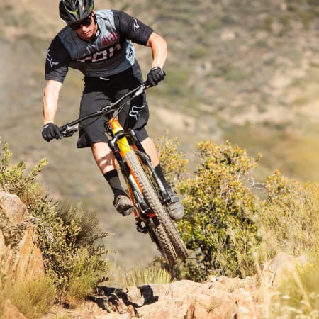 Cycliste en VTT enduro franchissant un terrain rocheux en montagne avec technique et équilibre