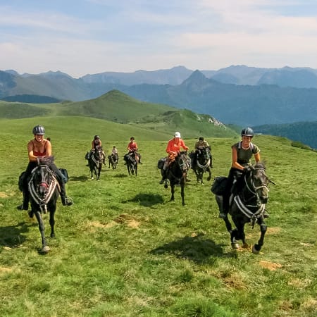 Groupe de cavaliers en randonnée équestre sur les crêtes verdoyantes des Pyrénées avec vue sur le massif de Tabes