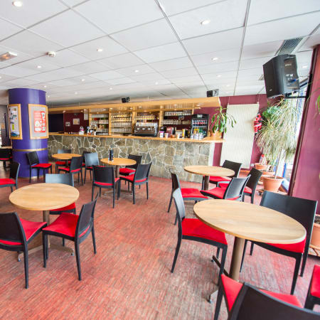 Espace d'accueil du centre UCPA Grand Serre Chevalier avec tables, chaises et bar de restauration