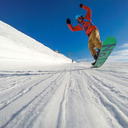 Snowboardeur en veste rouge sur piste bleue à Serre Chevalier sous ciel dégagé