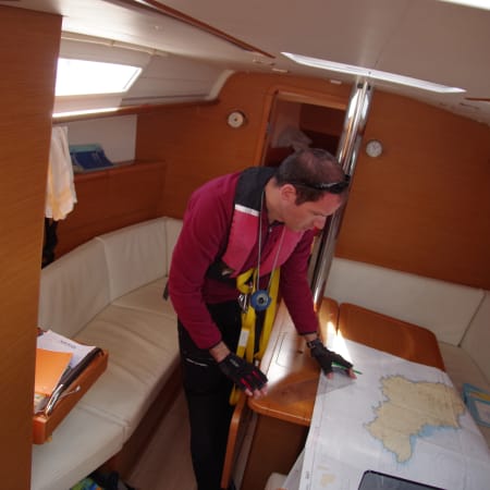Skipper consultant une carte de navigation à l'intérieur de la cabine d'un voilier de croisière UCPA