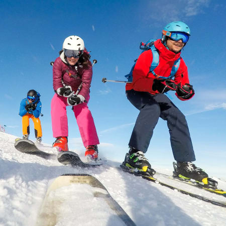 Enfants apprenant à skier en groupe sur pente enneigée avec moniteur en vêtements rouges