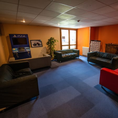 Espace détente du centre UCPA Grand Serre Chevalier avec canapés, console de jeux et salon de loisirs