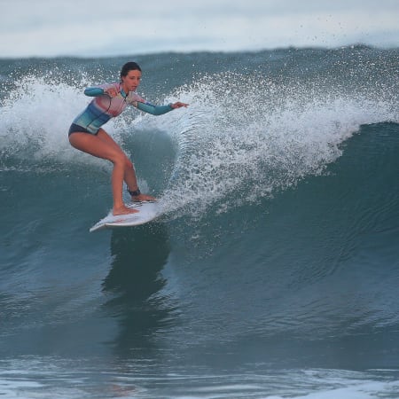 Jeune femme surfant une vague à Bombannes lors d'un séjour surf estival en océan