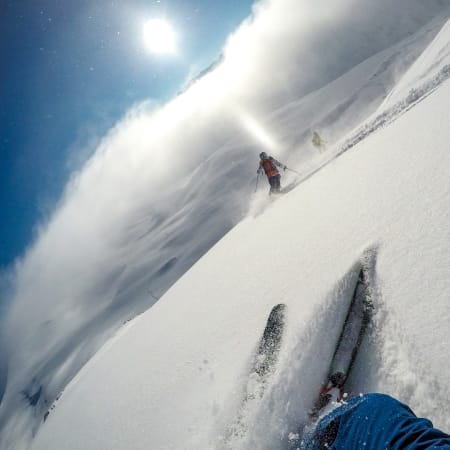 Skieur expert descendant une pente hors-piste enneigée en montagne avec équipement de sécurité