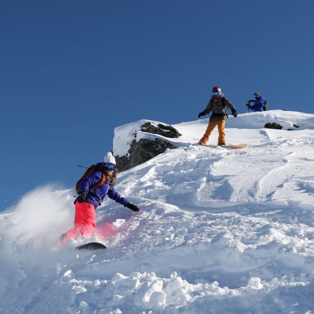 Groupe de snowboarders en action sur pente enneigée, formule Snowboard Pack Mi-temps pour niveaux initiés