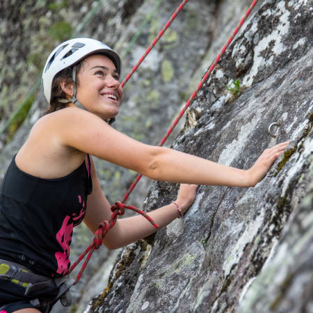 Grimpeuse en escalade sur une falaise rocheuse avec casque et cordes rouges en vallée de Chamonix