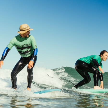 Deux surfeurs en combinaison pratiquant le surf sur les vagues de Bretagne lors d'une session de groupe