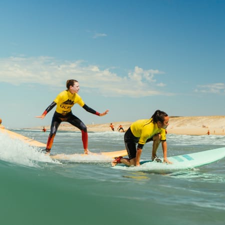 Deux surfeurs en combinaison jaune pratiquant le surf à Soustons pendant la semaine Sunny Week 18-30 ans