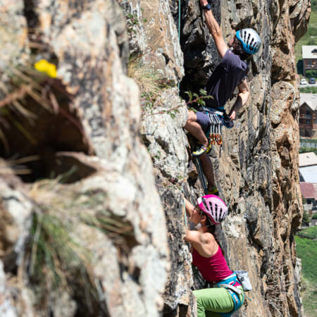 Grimpeur en escalade sur une falaise rocheuse à Serre Chevalier avec équipement de protection et casque