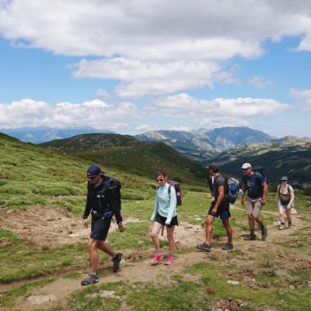 Groupe de randonneurs en montagne dans la vallée du Louron avec paysage pyrénéen et sommets enneigés