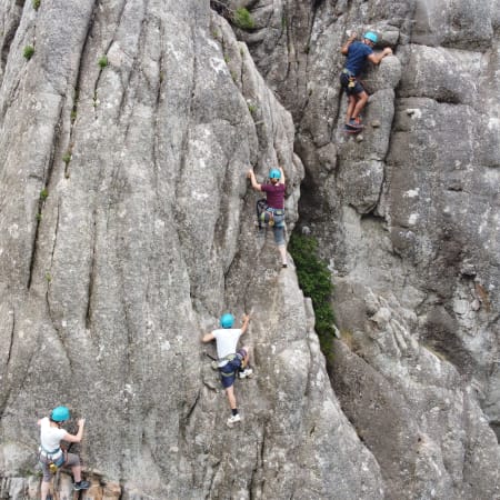 Groupe de grimpeurs pratiquant la via ferrata sur paroi rocheuse en Corse avec équipement de sécurité