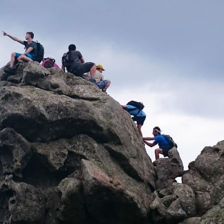 Groupe de randonneurs escaladant un rocher granitique en Corse lors d'une randonnée pédestre en montagne