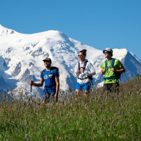 Groupe de randonneurs en trail running dans les Ecrins avec pic enneigé en arrière-plan par beau temps