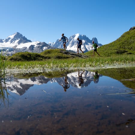 Randonneurs débutants sur sentier alpin du Mont-Blanc avec lac de montagne et pics enneigés en arrière-plan
