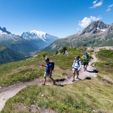 Randonneurs en montagne au pays du Mont-Blanc avec vue panoramique sur les pics enneigés et vallée alpine verdoyante