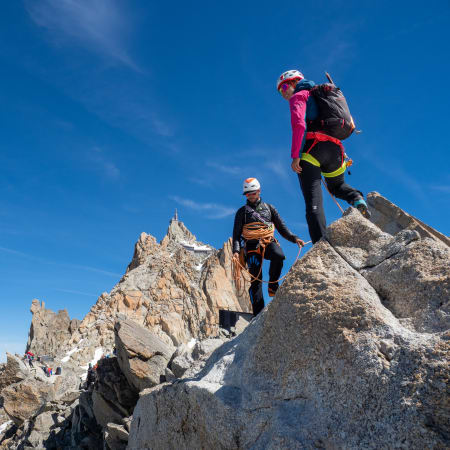 Jeunes alpinistes en escalade sur les rochers du Mont-Blanc avec équipement de sécurité et vue panoramique glaciaire
