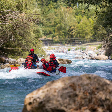 Groupe de rafters descendant l'Isère aux Arcs avec équipement de sécurité rouge sur eaux vives tumultueuses