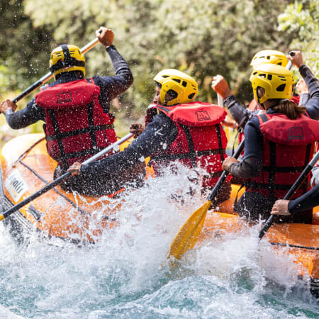 Groupe de pagayeurs en packraft naviguant les rapides de l'Isère avec casques jaunes et gilets de sauvetage rouges