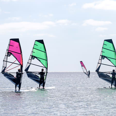 Windsurfeurs pratiquant en lagune bretonne avec voiles rose et verte, stage Full Windsurf 2 jours
