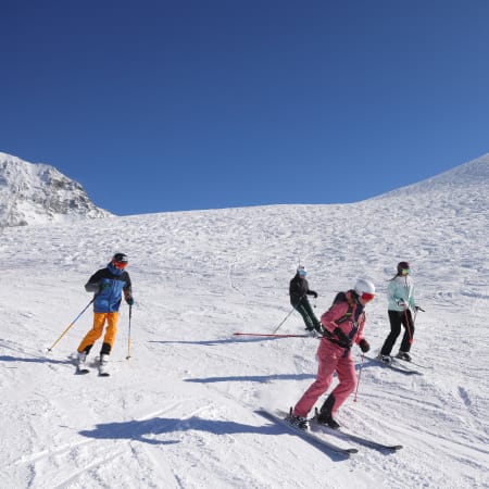 Groupe de jeunes skieurs en cours de ski aux Arcs sur piste enneigée avec paysage montagneux