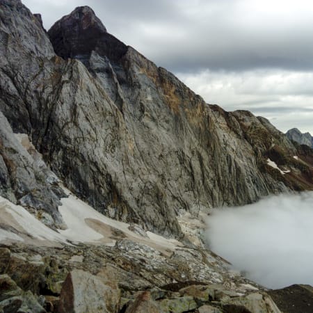 Cirque glaciaire des Pyrénées avec parois rocheuses escarpées et vallée couverte de nuages bas