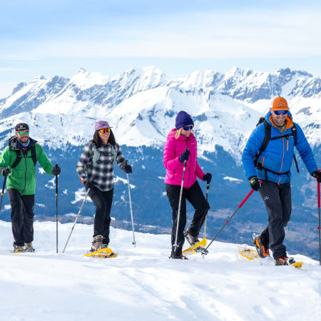 Groupe de randonneurs en raquettes à neige en Italie avec montagnes enneigées et paysage alpin en arrière-plan