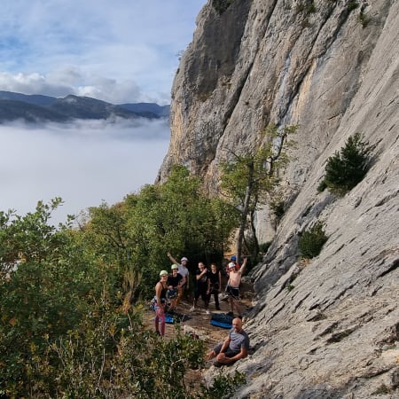 Groupe de grimpeurs au pied de falaises calcaires d'Orpierre avec vallée brumeus en arrière-plan