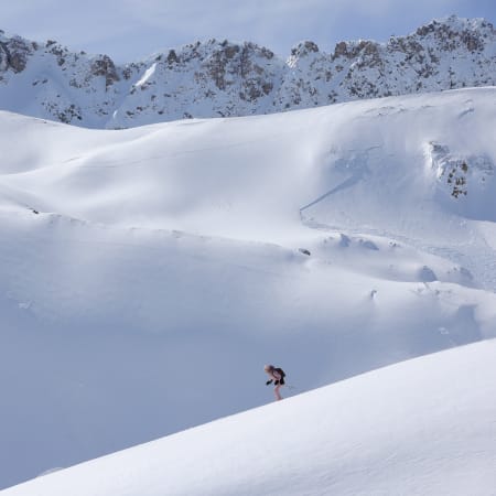 Skieur en descente hors-piste à Serre Chevalier avec pentes enneigées et pics rocheux en arrière-plan
