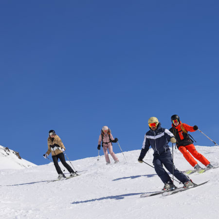 Groupe de jeunes skieurs en cours collectif sur les pistes enneigées des Arcs sous ciel bleu