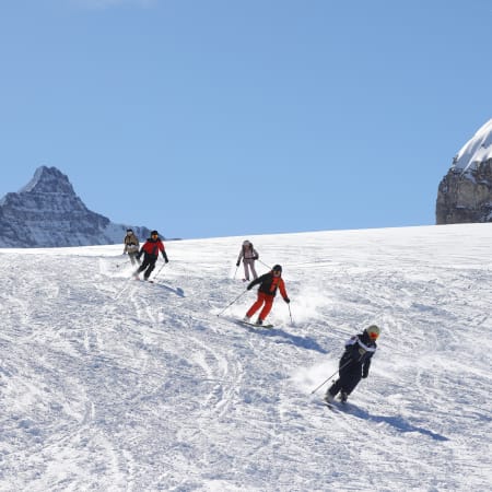 Groupe de skieurs en formation sur piste bleue à Serre Chevalier avec moniteur, paysage montagneux enneigé