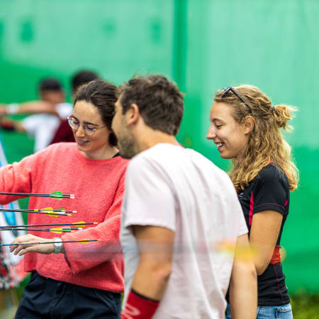 Groupe de jeunes adultes découvrant le tir à l'arc en intérieur à la station des Arcs lors du séjour multisport