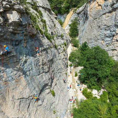 Grimpeurs pratiquant l'escalade et le yoga en falaise avec vue aérienne sur la paroi rocheuse et la végétation environnante
