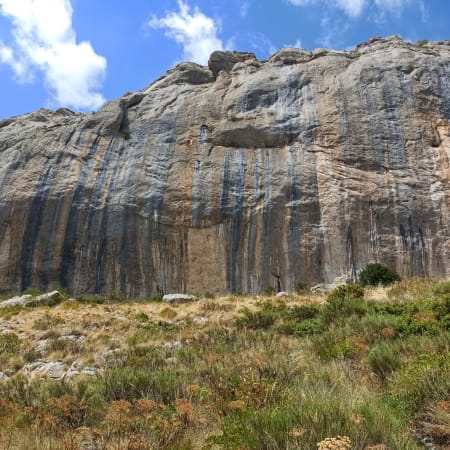 Falaise calcaire d'Orpierre avec voies d'escalade et végétation méditerranéenne sous ciel bleu