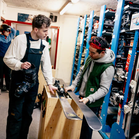 Moniteur de ski présentant une planche à un jeune client dans un magasin de location d'équipements de ski à Chamonix