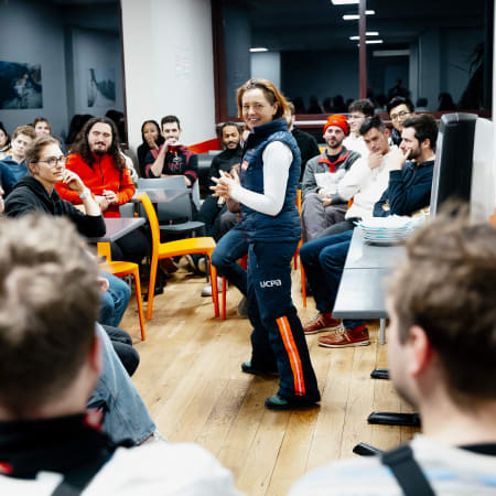Groupe de jeunes adultes réunis dans une salle pour la semaine Fresh Fresh Week, animateur en gilet bleu présentant le programme snowboard à Chamonix