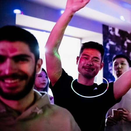 Groupe de jeunes skieurs célébrant dans une ambiance de soirée colorée avec lumières néon roses et bleues