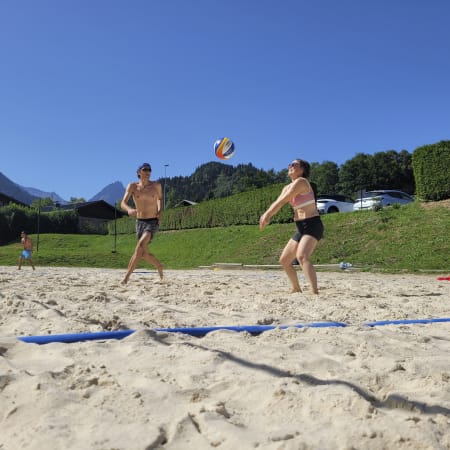 Joueurs de volley-ball sur plage de sable aux Contamines avec montagnes en arrière-plan et multisports d'été