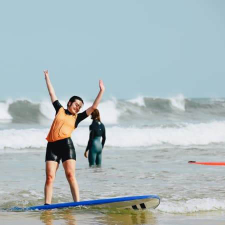 Jeune surfeur célébrant sur sa planche dans l'océan lors d'une semaine surf et yoga à Soustons