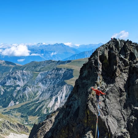Grimpeur en highline sur paroi rocheuse avec vue panoramique sur les falaises et vallées d'Orpierre